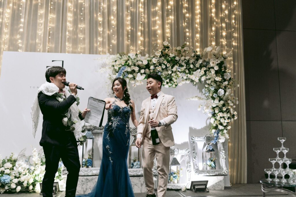 Event photo of wedding emcee entertaining the couple during the wedding banquet.